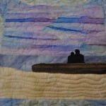 couple sitting on log at the beach